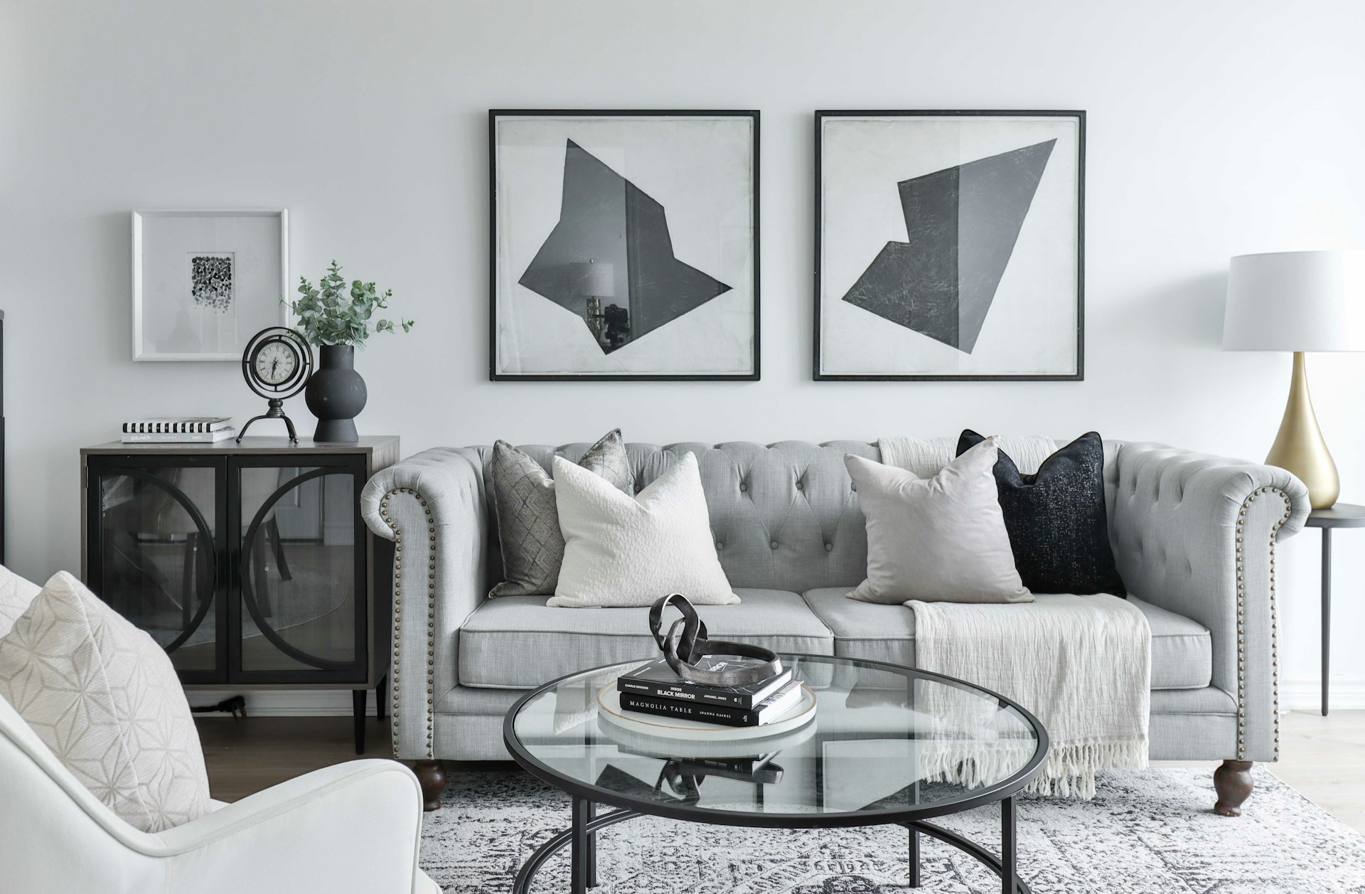 Ambiente interno moderno com sofá cinza, quadros abstratos e elementos decorativos.